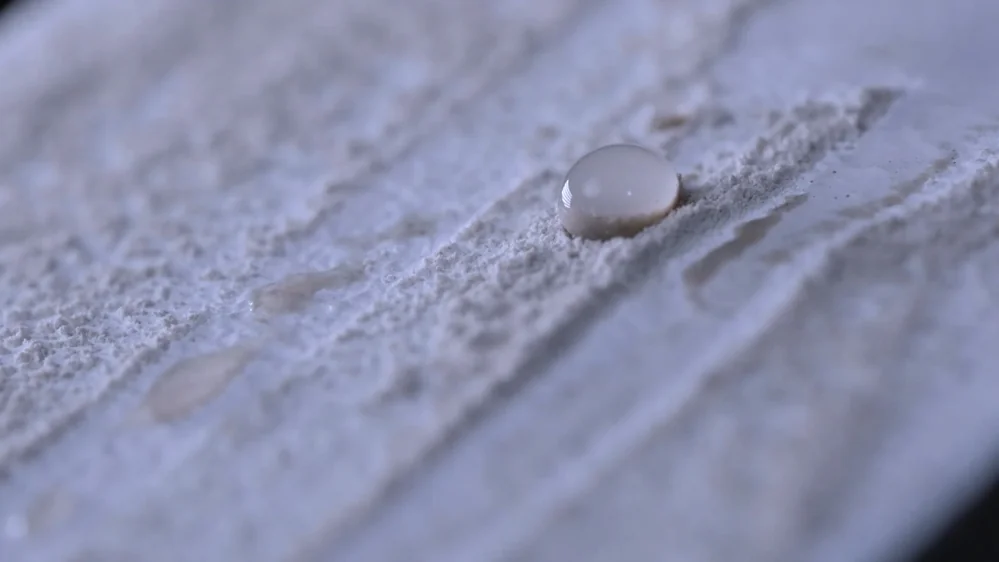 A self-cleaning surface showing dirt gathering in water bead